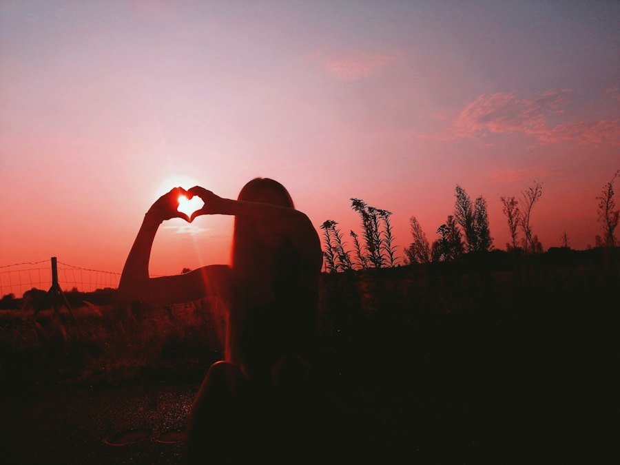 Heart-shaped hands at sunset