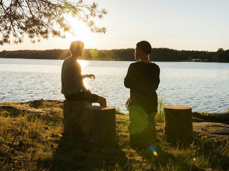 Two people talking by a lake