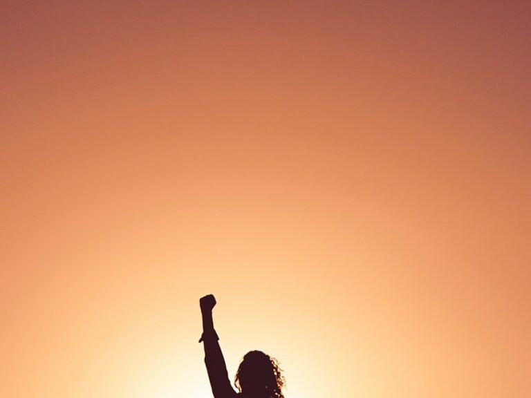Person with raised arms at sunset