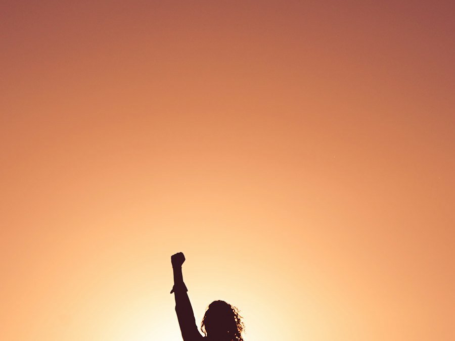 Person with raised arms at sunset